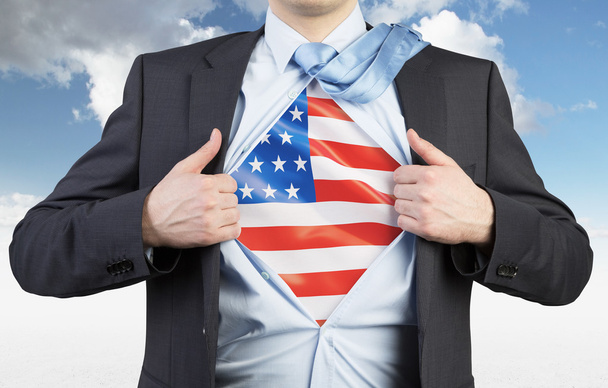 A man tearing the shirt. US flag on the chest. Cloudy sky background. - Foto, imagen