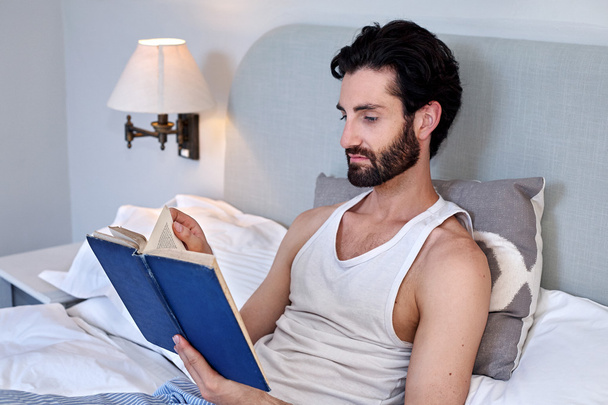 man on bed reading book - Foto, Imagen