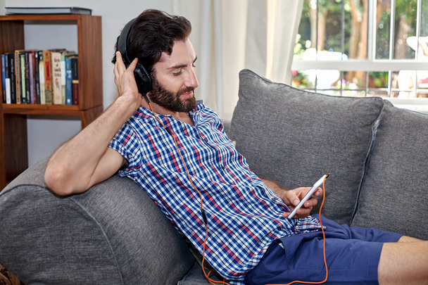 man listening music on sofa - Photo, image
