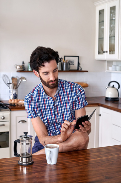 Man enjoying coffee with cellphone at home - Foto, Imagen