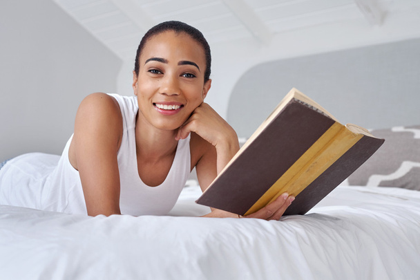 woman laying on bed reading book - Фото, изображение
