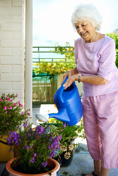 retired woman watering her plants - Фото, изображение