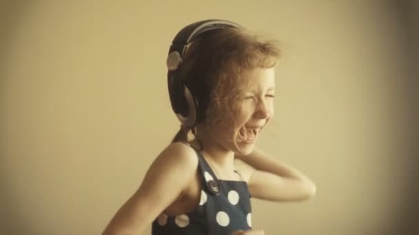 fröhliches kleines Mädchen, das mit Kopfhörern tanzt. Zeitlupe. - Filmmaterial, Video