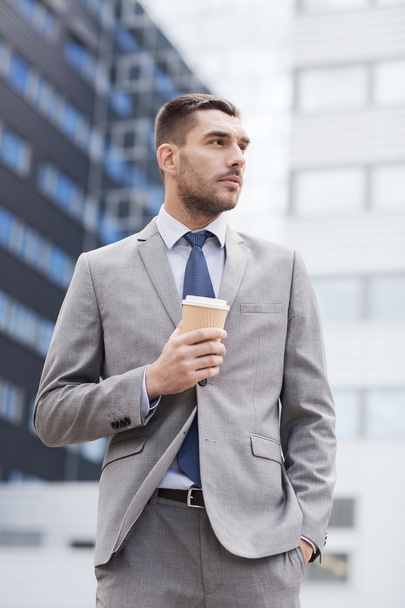 young serious businessman with paper cup outdoors - Φωτογραφία, εικόνα