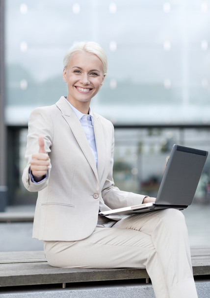 smiling businesswoman working with laptop outdoors - Foto, Imagen