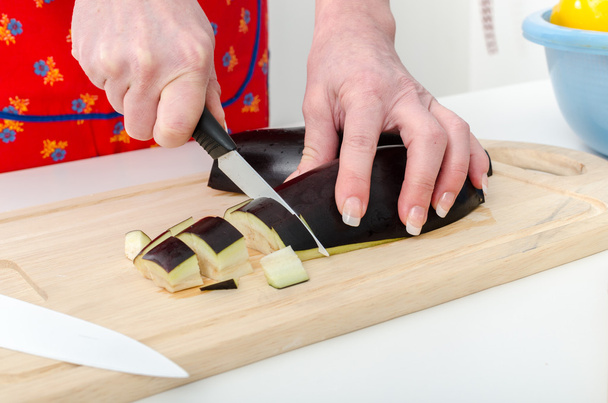 Mãos de mulher cortando berinjela
 - Foto, Imagem