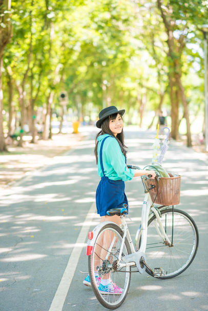 Asian young woman with a bike in a summer park. - Foto, afbeelding