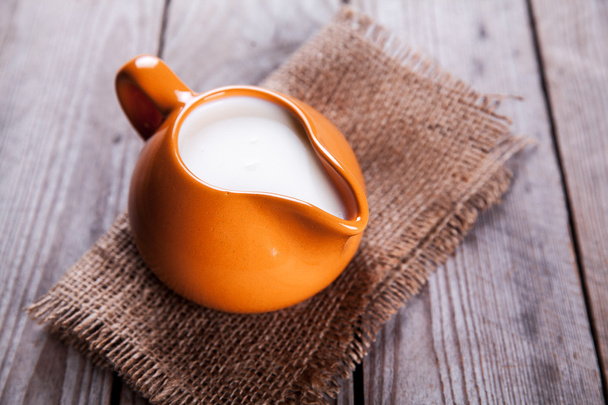 healthy drink. orange clay jug with milk in a rustic style on a wooden background - Fotografie, Obrázek