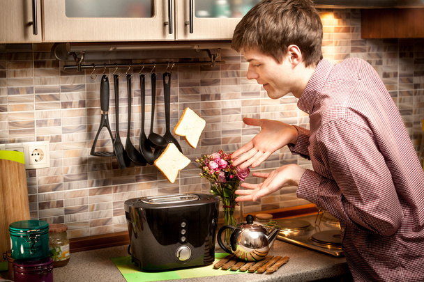 young man trying to catch toasts popping out of toaster - Photo, Image