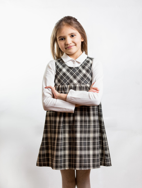 shy schoolgirl in checkered dress against white background - Zdjęcie, obraz