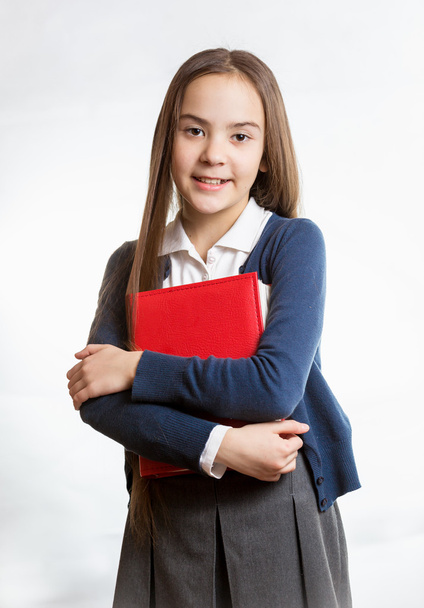 улыбающаяся школьница позирует с красной книгой против изолированного бэкгро
 - Фото, изображение