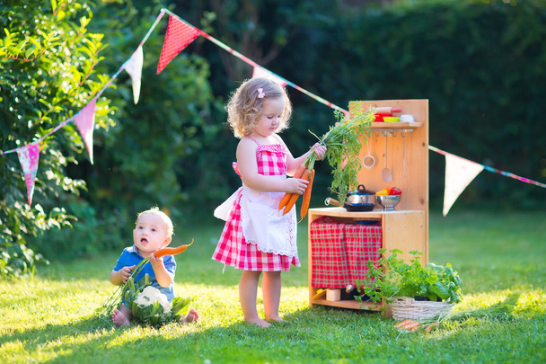Kinderen spelen met speelgoed keuken in een zomertuin - Foto, afbeelding
