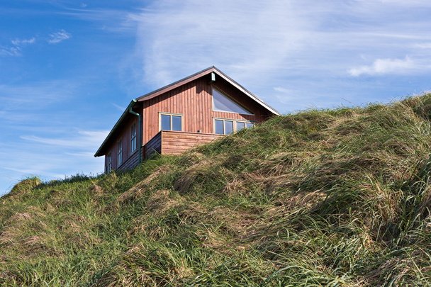 Traditional danish house in the sand dune with blue sky and green grass - Photo, Image