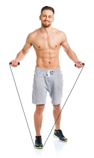 Atletische aantrekkelijke man springen op een touw op de witte - Foto, afbeelding
