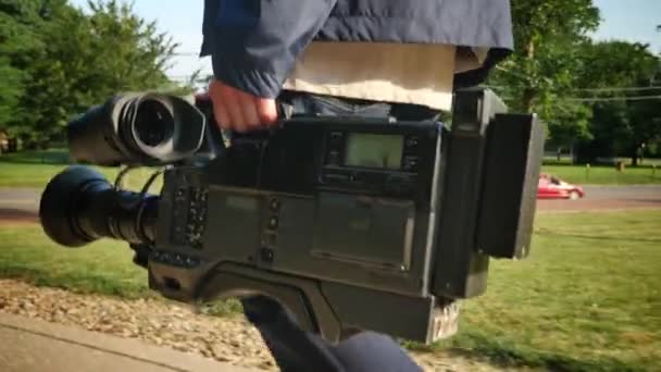 A low angle shot of a cameraman carrying his video camera to a production. - Footage, Video