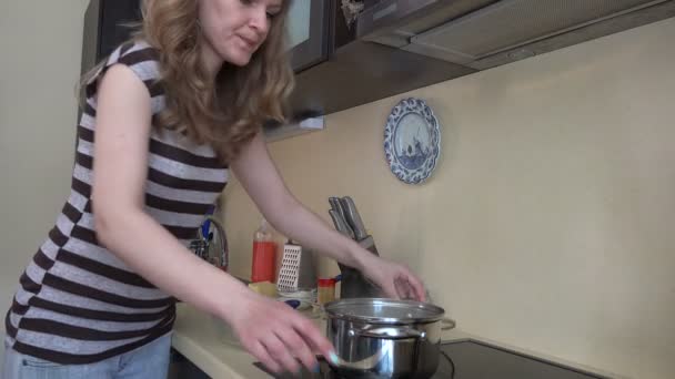 housewife girl take boiled spaghetti from pot to glass dish. 4K - Footage, Video