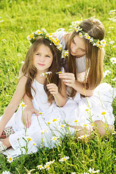 Two pretty girls with wreath of chamomiles - Foto, afbeelding