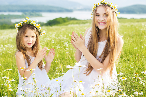 Two friends girls at meadow of chamomiles - Φωτογραφία, εικόνα