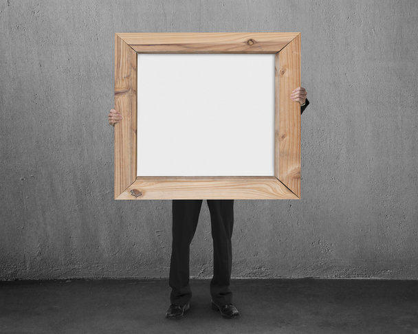 man hold blank whiteboard with wooden frame in concrete room - Valokuva, kuva