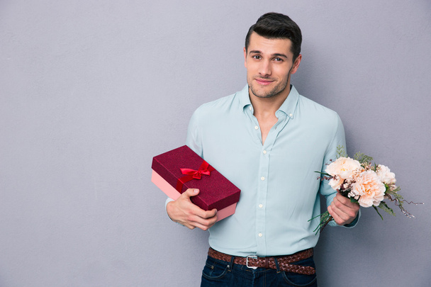 Young man holding gift box and flowers - Foto, immagini