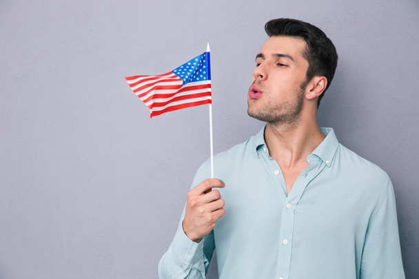 Young man blowing on US flag - Φωτογραφία, εικόνα