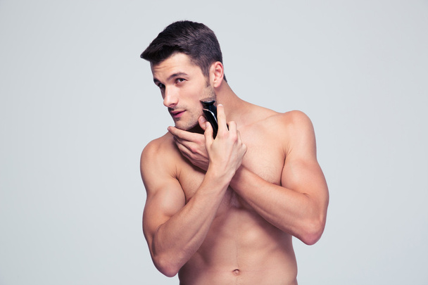 Young man shaving with electric shaver - Photo, Image