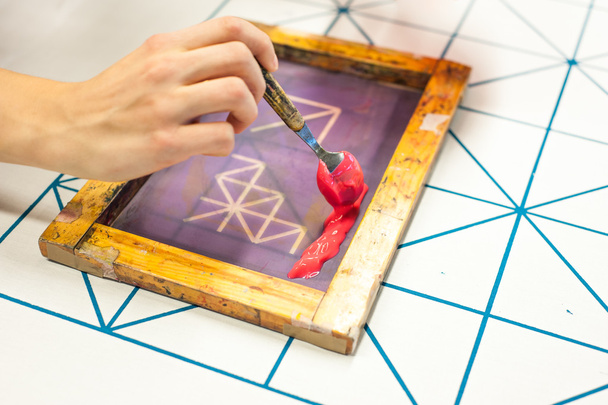 Hand applying paint to a screen printing design - Photo, Image