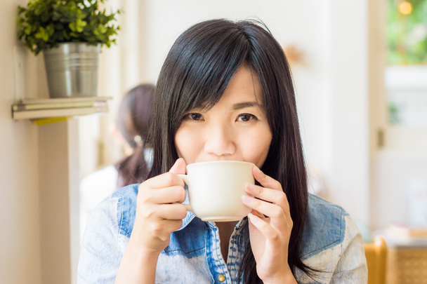 Vrouw met kop koffie glimlachend in café - Foto, afbeelding