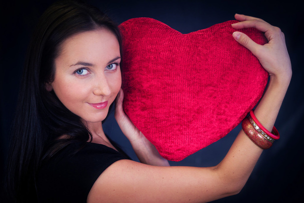 Woman with heart shaped cushion - Foto, afbeelding