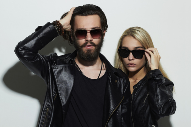 gorgeous fashion beautiful couple in black clothes wearing trendy glasses together. Hipster boy and girl. Bearded young man and blonde in sunglasses - Photo, Image