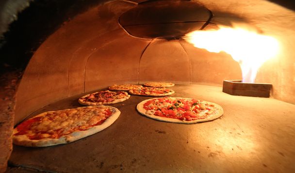 pizzas en el horno con la llama caliente
 - Foto, imagen