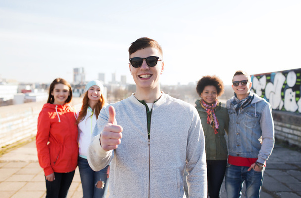 happy teenage friends showing thumbs up on street - Photo, Image