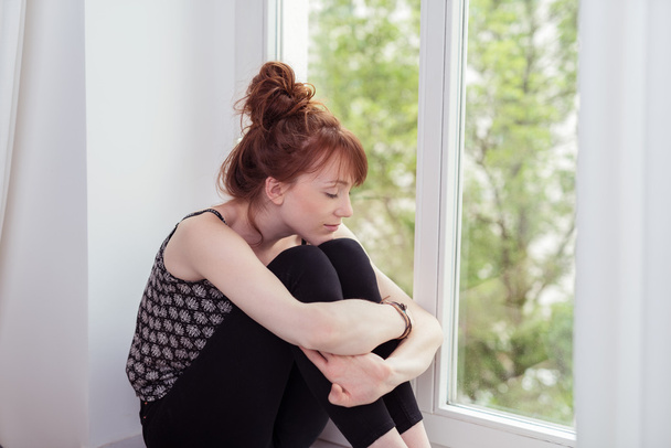 Pensive Girl Hugging her Knees at the Window - Фото, изображение