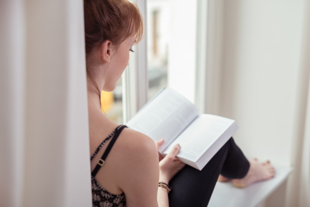 Jeune femme pieds nus se détendre avec un livre
 - Photo, image