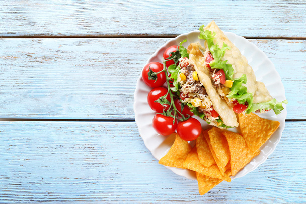 Tasty taco with nachos chips and vegetables on plate on table close up - Фото, изображение