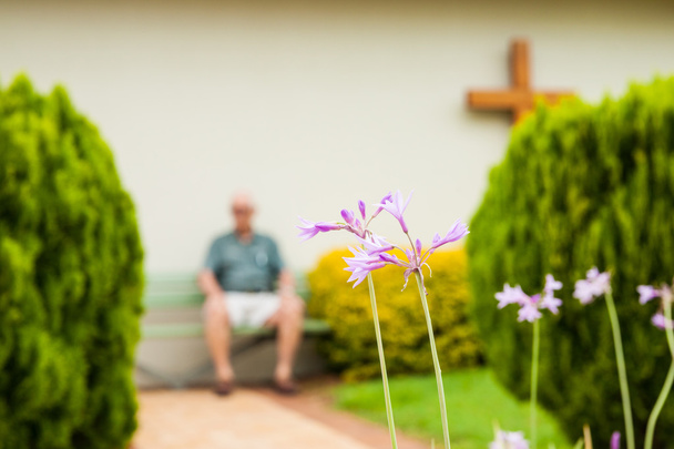 Unerkennbar verschwommener Senior sitzt in Gedanken vor religiösem Gebäude - Foto, Bild