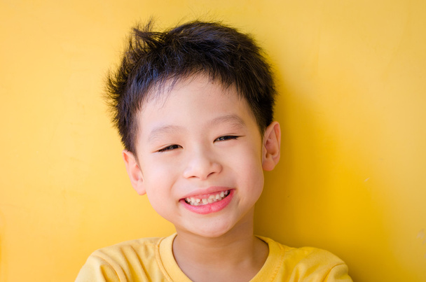 Sarı duvar arka plan üzerinde gülümseyen çocuk - Fotoğraf, Görsel