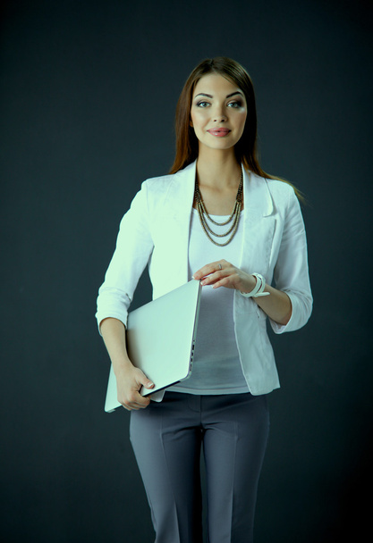 Young woman holding a laptop, standing on gray background - Foto, Bild