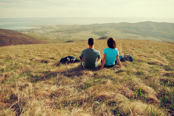 Любящая пара, сидящая на лугу на открытом воздухе
 - Фото, изображение