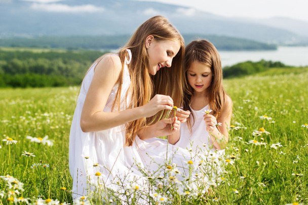 Two pretty friends girls at meadow of chamomiles - Fotó, kép