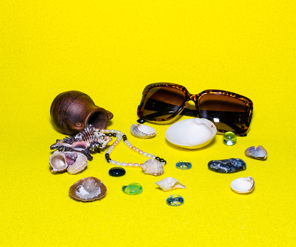 parel kralen, antieke Amfora en zee schelp op een gele pagina - Foto, afbeelding