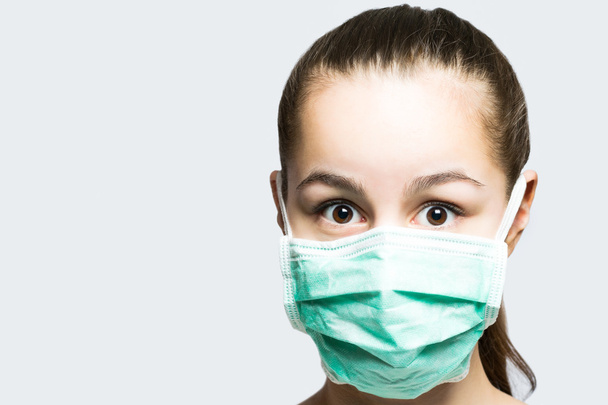 Young girl in doctors mask looking surprised and shocked - Foto, Imagen