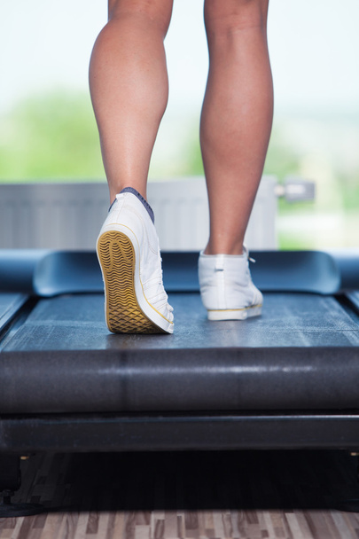 Fitness girl running on treadmill. Woman with muscular legs in gym - Фото, зображення