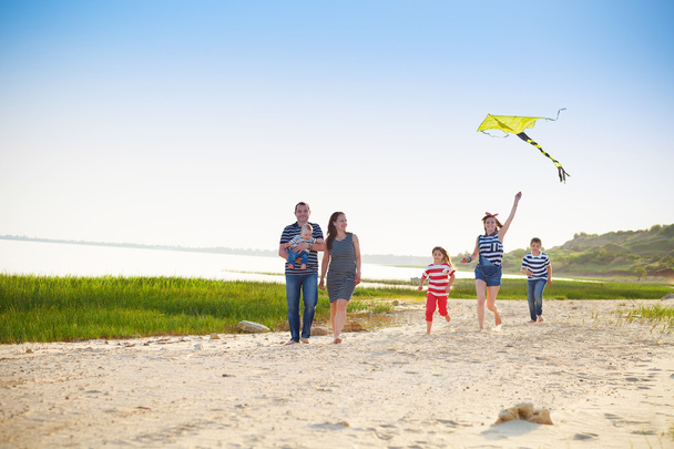 Felice giovane famiglia con volare un aquilone sulla spiaggia
 - Foto, immagini
