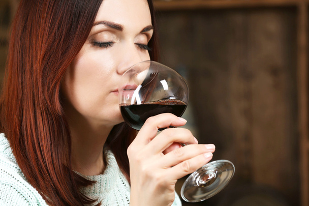 Young woman tasting wine in cellar - Фото, изображение