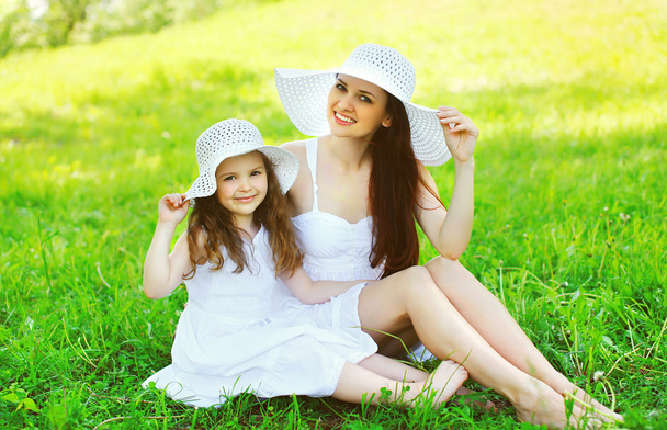 Happy smiling mother and daughter child wearing a white straw ha - 写真・画像