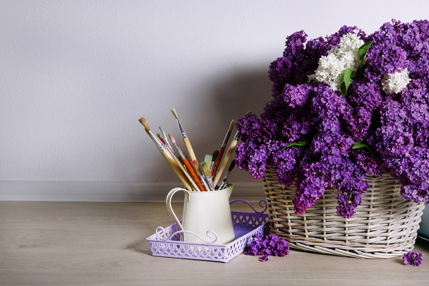 Beautiful lilac flowers on basket on floor in room close-up - Foto, imagen