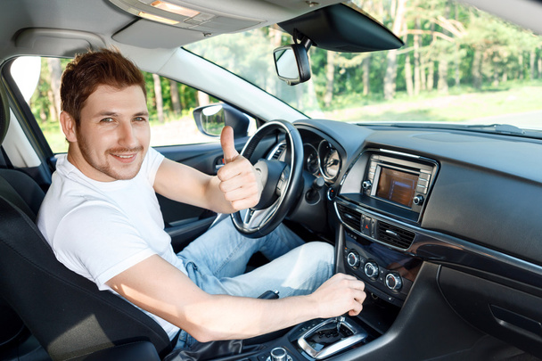 Smiling man thumbing up inside car - Φωτογραφία, εικόνα