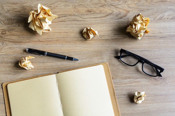 Crumpled paper balls with eye glasses and notebook on wood desk - Φωτογραφία, εικόνα