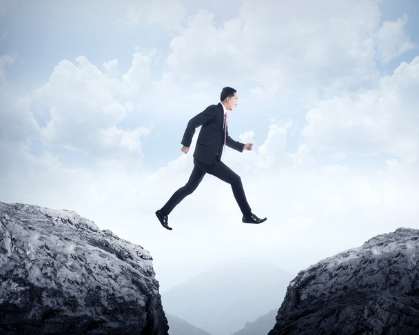 Business man jumping across hill - Photo, Image